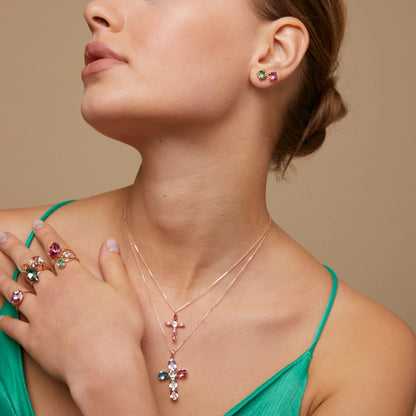 Woman wearing a necklaces, rings, and earrings with swarovski crystals on a beige background