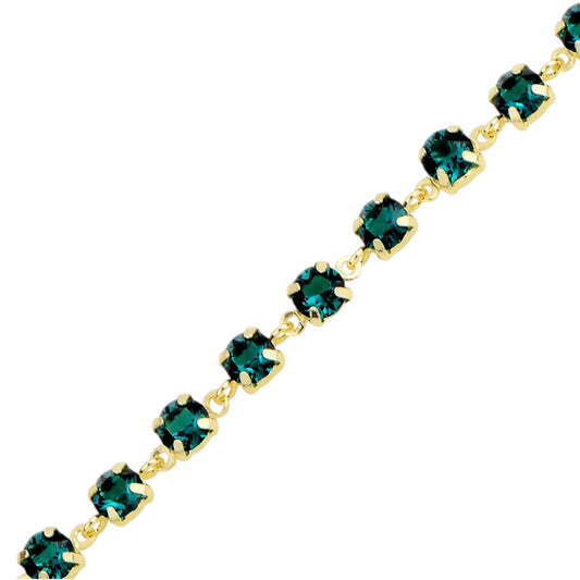 Gold bracelet with green swarovski crystals on a white background