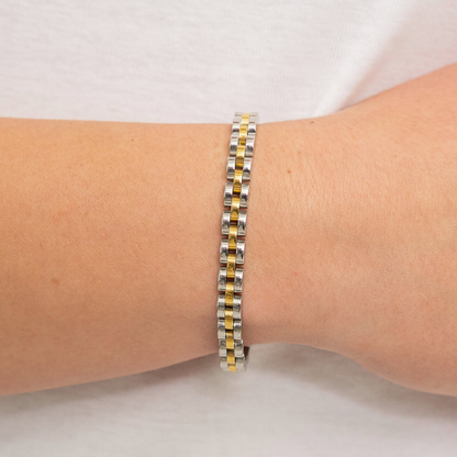 Gold watch band on a wrist with a plain background