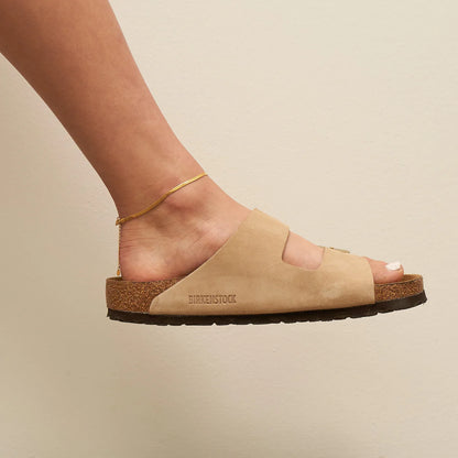 Beige sandal with 'Birkenstock' branding on a neutral background