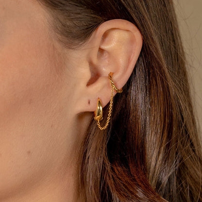 Gold hoop earrings worn by a person with brown hair.