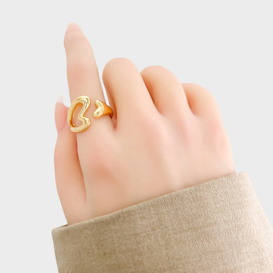 Gold ring on a hand against a light gray background