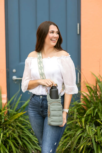 Woman holding a green bag and black container in front of a blue door.