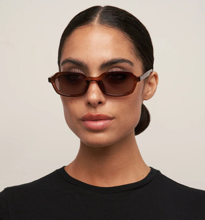 Woman wearing brown sunglasses with a plain background