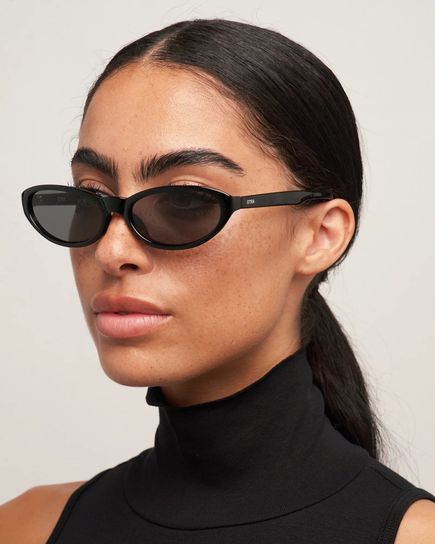 Woman wearing black sunglasses with a plain background