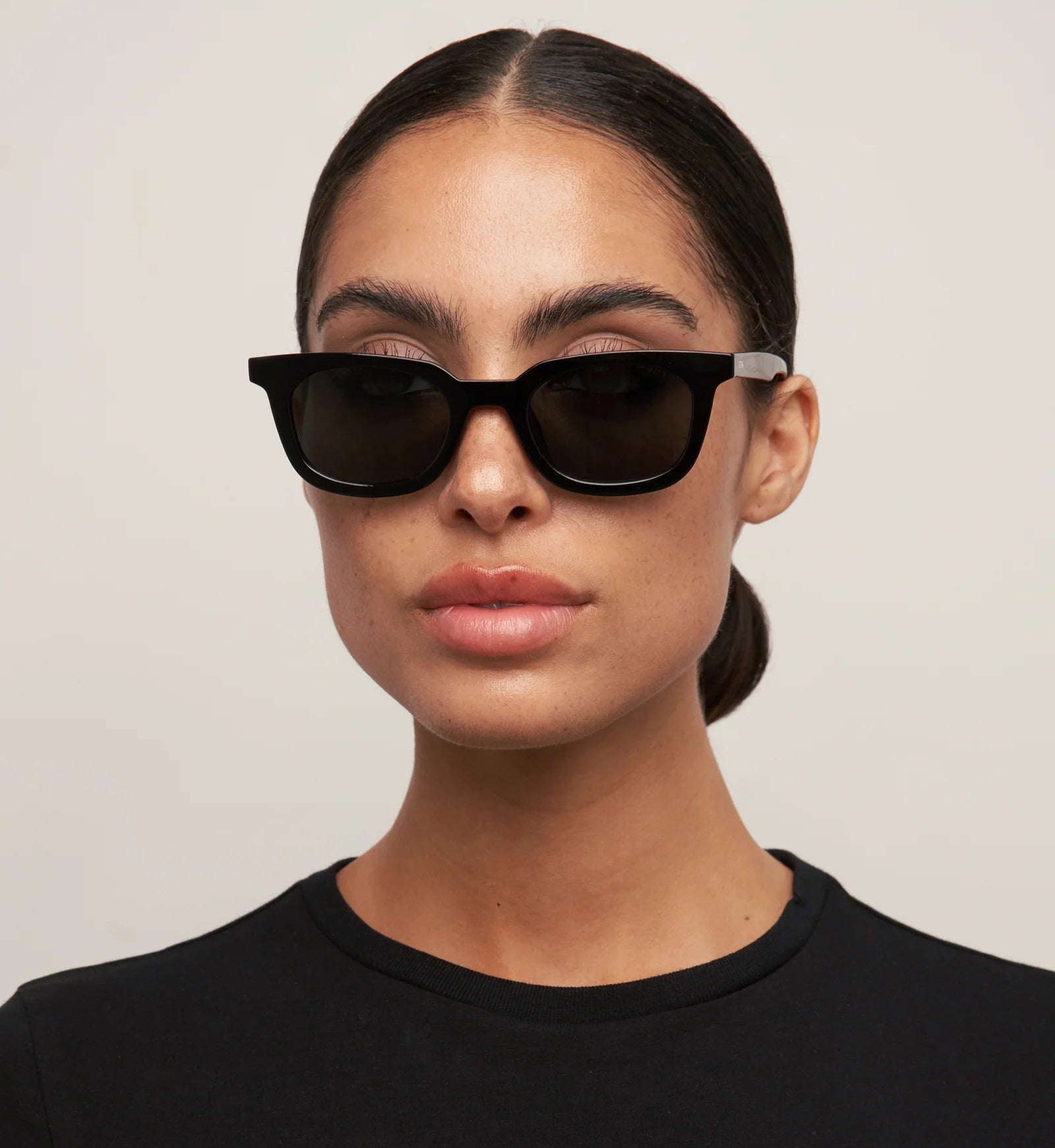 Woman wearing black sunglasses against a plain background