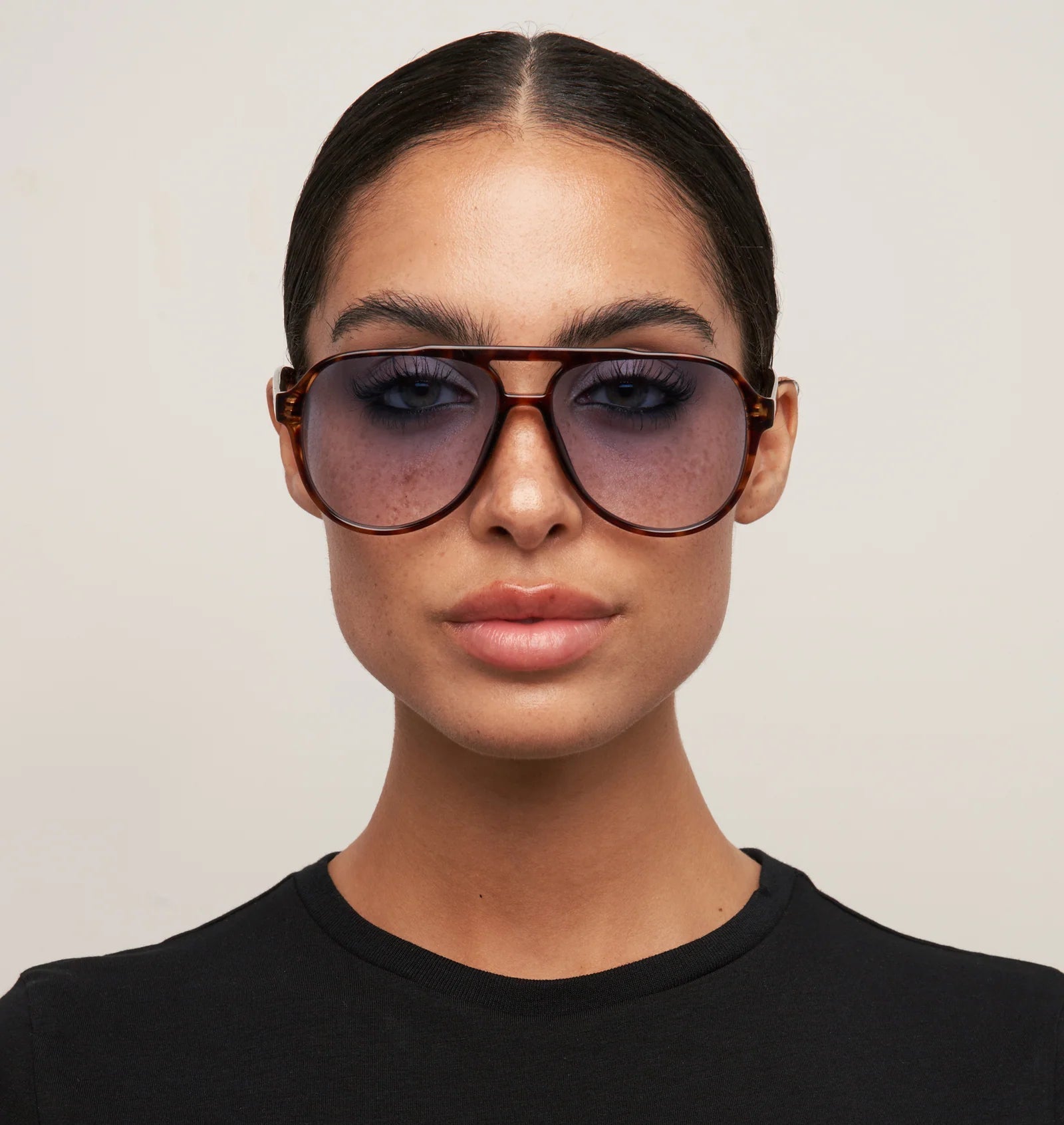 Person wearing large sunglasses with a neutral background