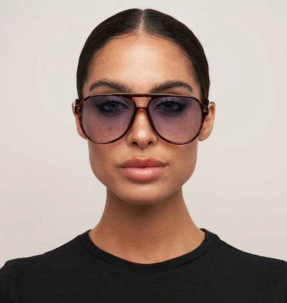 Person wearing large sunglasses with a neutral background