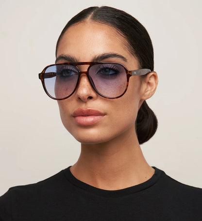 Woman wearing large sunglasses with a neutral background