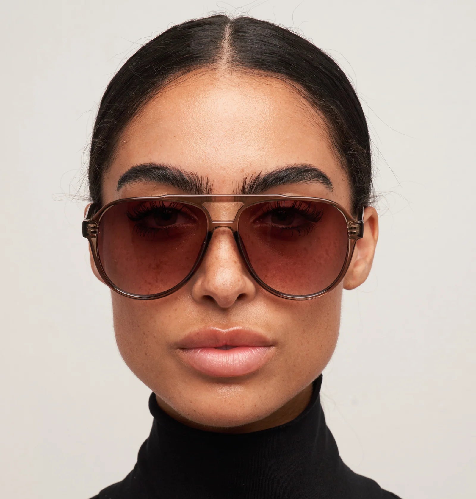 Woman wearing large sunglasses with a plain background