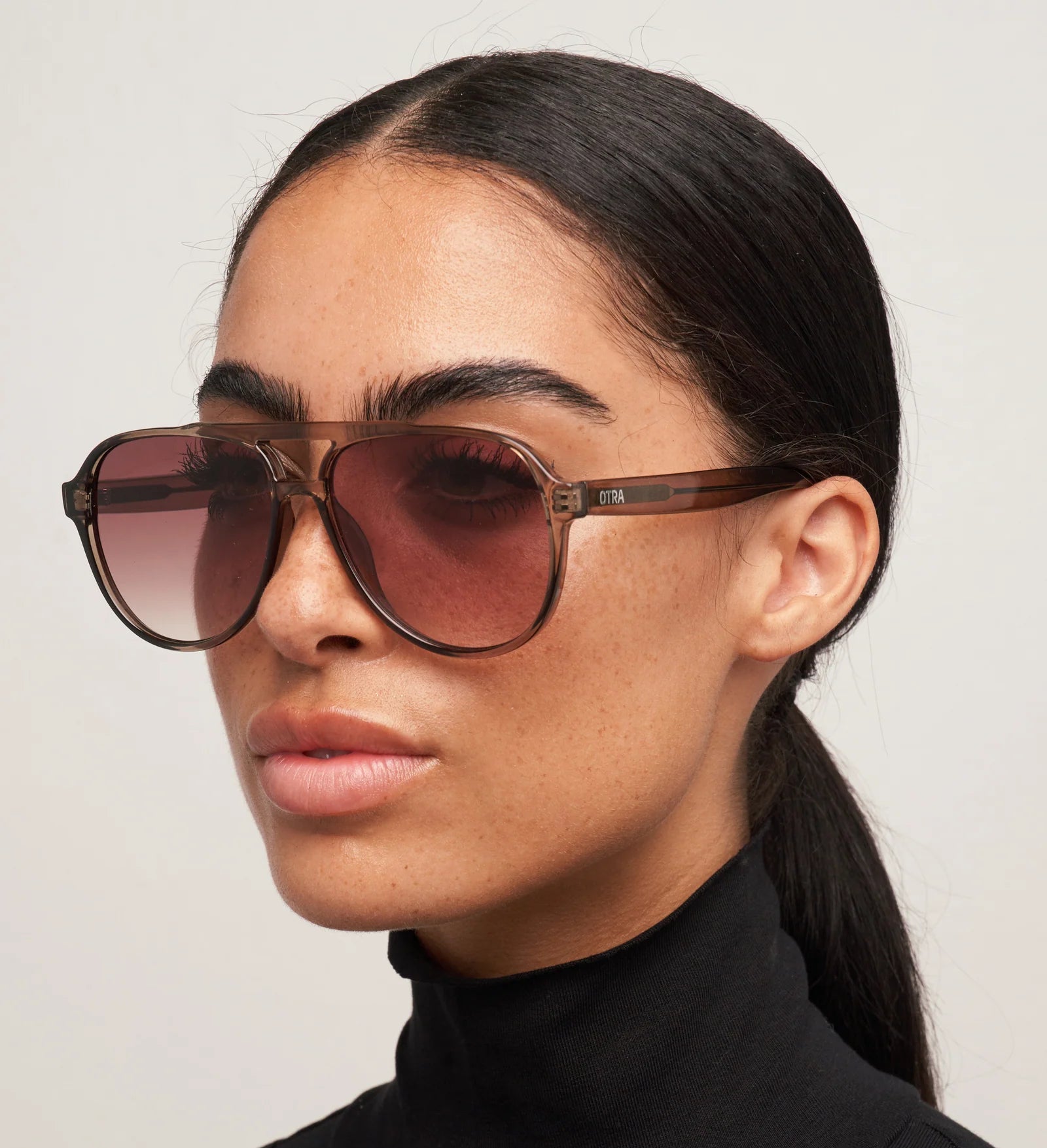 Woman wearing brown sunglasses with a plain background