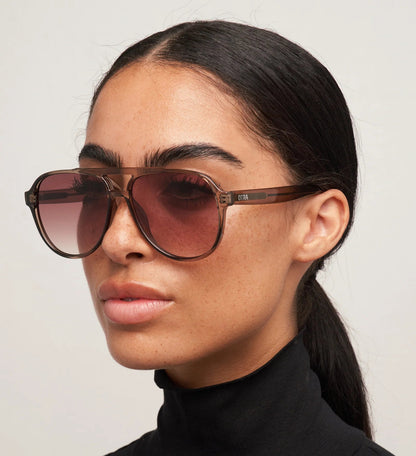 Woman wearing brown sunglasses with a plain background