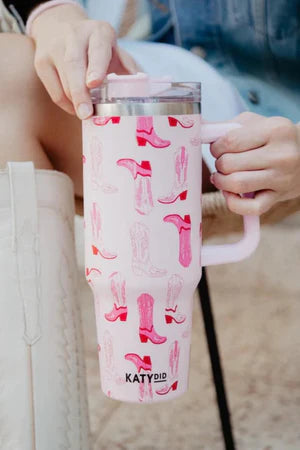 Pink tumbler with red boot pattern held by a person, brand 'KATYDID' visible