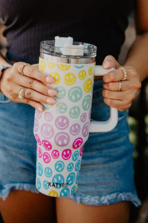 Person holding a colorful tumbler with smiley face pattern
