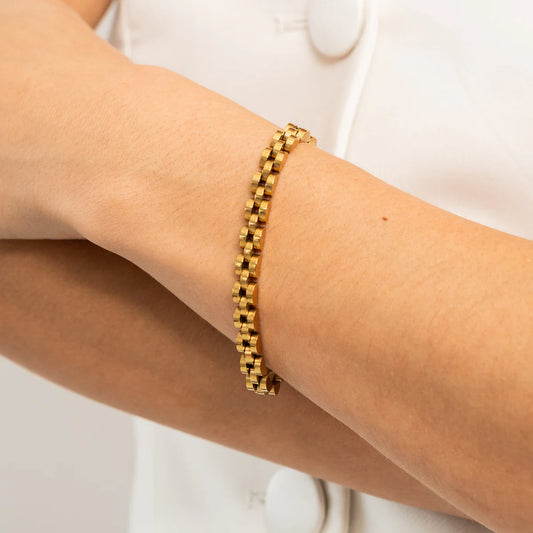 Gold bracelet on a person's wrist against a white background