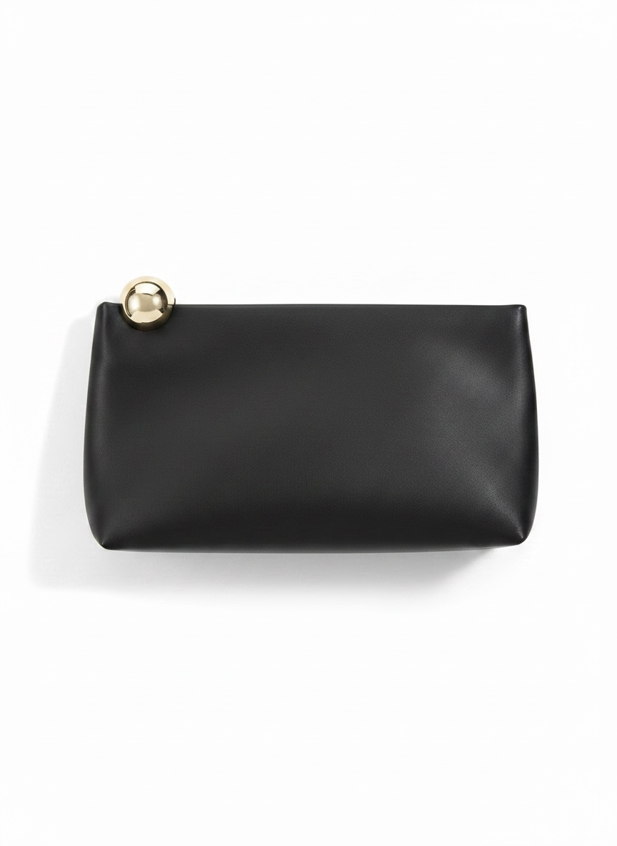 A black leather clutch bag with a small gold-tone metal sphere accent on the top left corner, photographed on a clean white background.