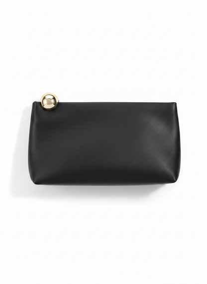 A black leather clutch bag with a small gold-tone metal sphere accent on the top left corner, photographed on a clean white background.