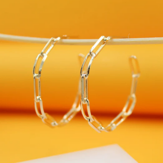 Gold hoop earrings on a yellow background