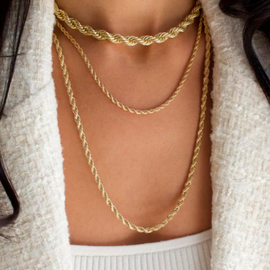 Gold chain necklace worn by a person with a white sweater