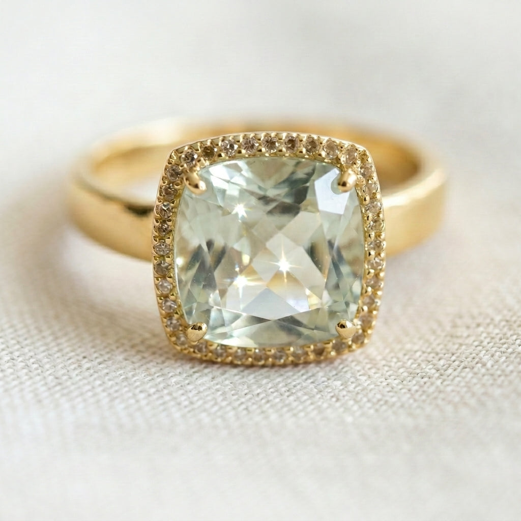 Gold ring with a large praziolite gemstone on a light fabric background