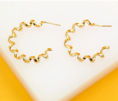 Gold spiral-shaped earrings on a white and orange background