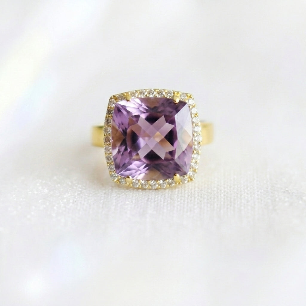 Ring with a purple gemstone and gold accents on a white background