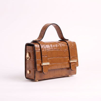 A structured brown crocodile-embossed leather handbag with a top handle, gold-tone hardware, and a front flap closure, photographed on a clean white background.
