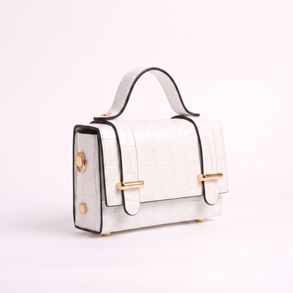 A structured white crocodile-embossed handbag with black trim, gold-tone hardware, and a top handle, photographed on a clean white background.