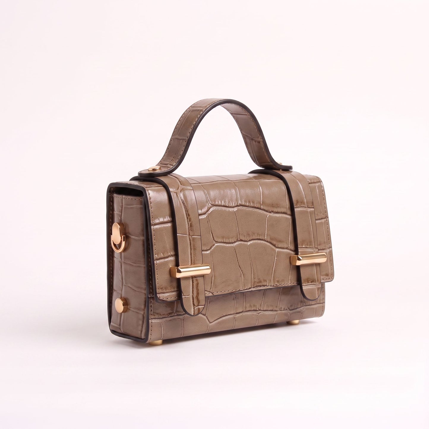 A structured handbag with a crocodile-embossed texture in taupe-brown, featuring gold-tone hardware and a top handle, set against a plain light background.